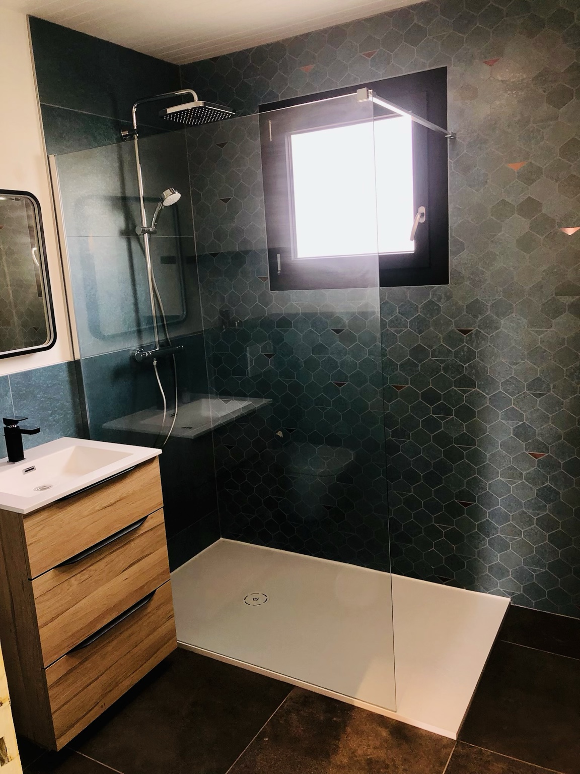 Salle de bains rénovée avec douche vitrée, faïence bleu profond et meuble bois
